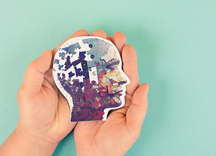 Hands holding image of head filled with puzzle pieces